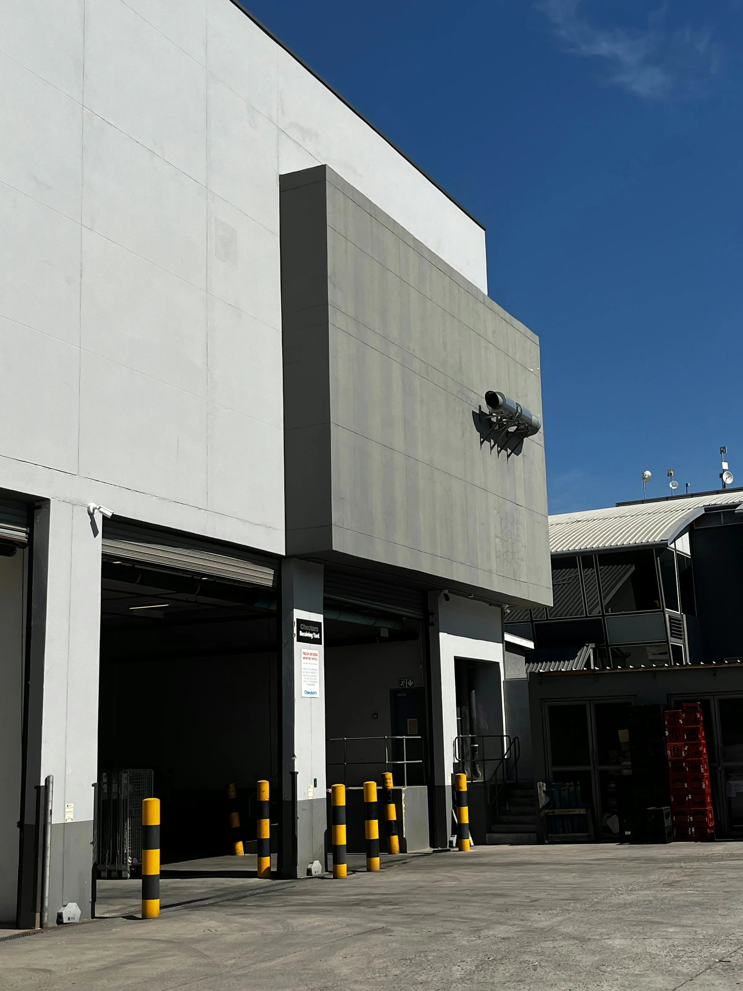 Working industrial building exterior with surveillance cameras covering its loading entrances
